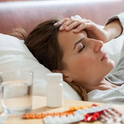 Woman resting in bed, illustrating the daily toll of living with a chronic health condition