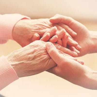Close-up of a younger person gently holding the hands of an older person, conveying care and support.