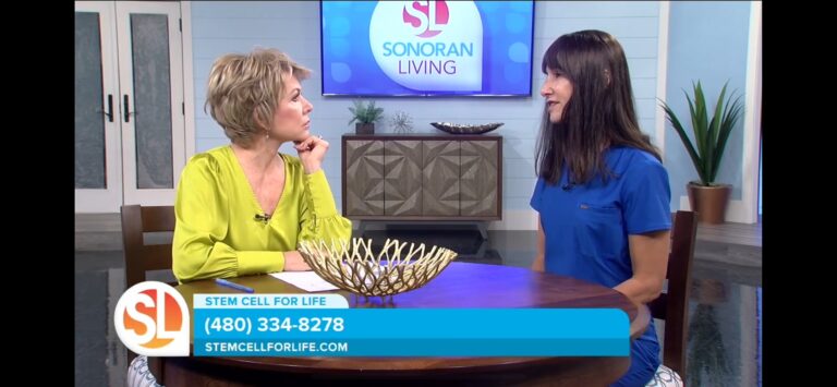 Two women sit across from each other talking in a TV studio set, with a "Sonoran Living" screen and a blue banner showing "Stem Cell For Life" contact details.